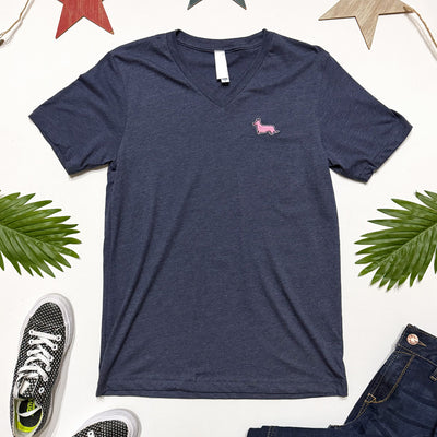 Navy blue t-shirt with a pink logo on a white background with sneakers and jeans.