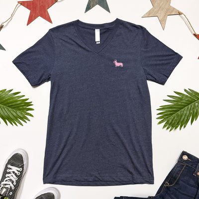 Navy blue t-shirt with a pink logo on a white background with sneakers and jeans.